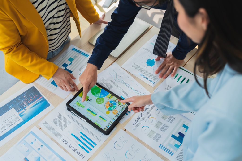 personas revisan diferentes gráficas sobre una mesa