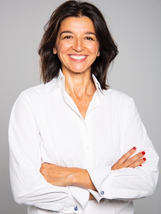Fotografía en plano medio a calor de una mujer morena sonriendo a cámara