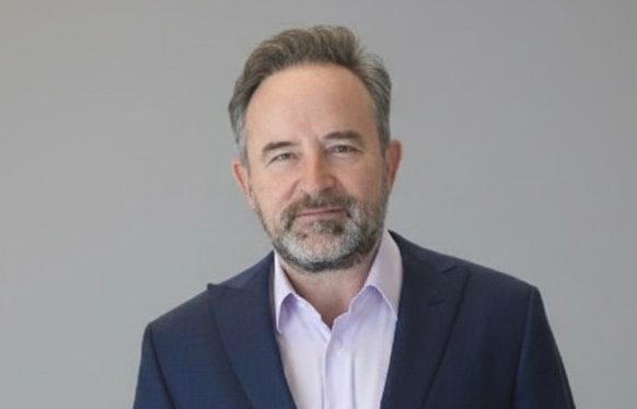 Fotografía en primer plano a color de un hombre sonriendo a cámara